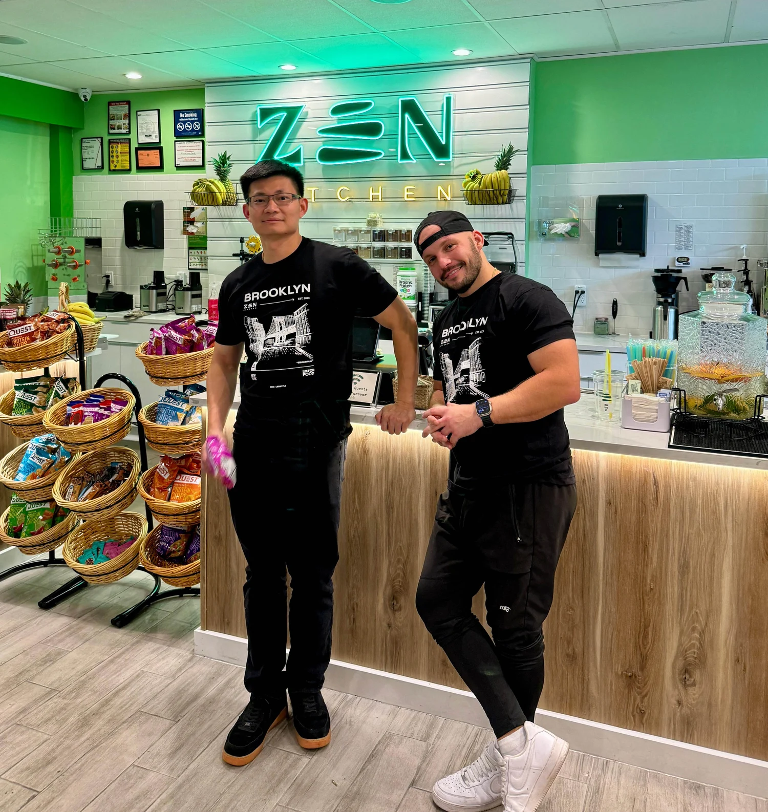 Eugene and Jian, Zen Kitchen founders, in front of the Zen neon sign in Brooklyn